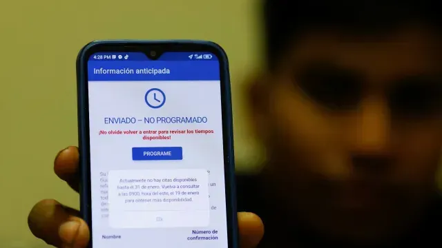 Migrantes que buscan asilo en EE. UU. utilizan sus teléfonos para solicitar una cita en un puerto de entrada terrestre.