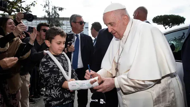 El papa firma yeso del brazo de un niño. Foto: EFE