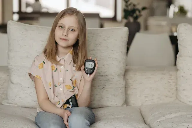 Niña con diabetes mide su nivel de azúcar en la sangre con un glucómetro