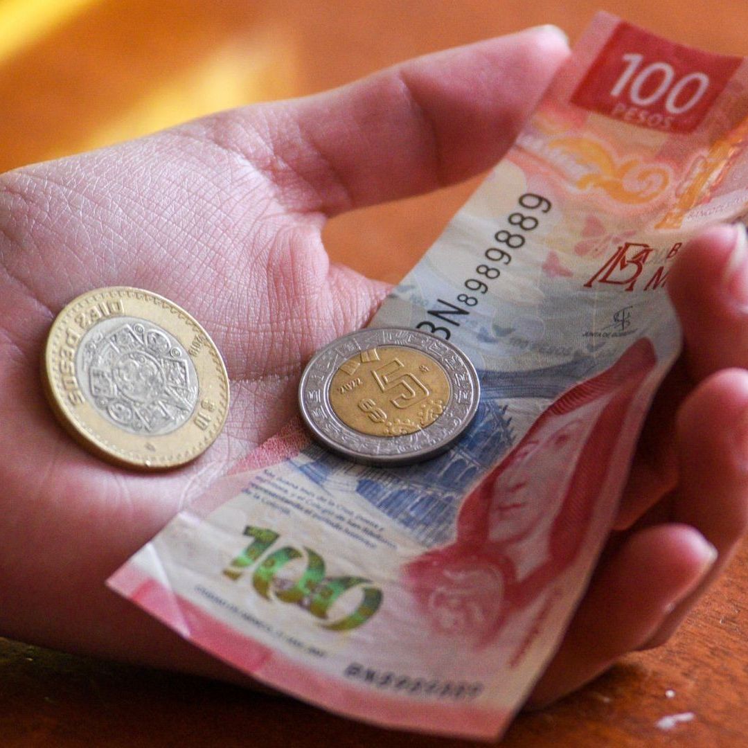 La mano de una persona sostiene billetes y Monedas por Prima Vacacional 2026
