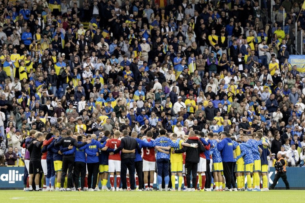 Los jugadores de Dinamarca y Ucrania cubren a su compañero Christian Eriksen. Foto: AFP