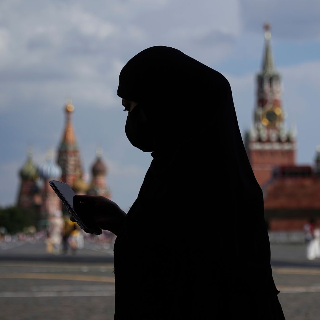 Una mujer, vestida con niqab, consulta su celular mientras camina por la Plaza Roja, en Moscú, Rusia. Foto: AP