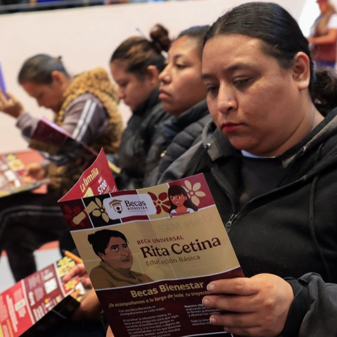 Mamá sostiene folleto de información de la Beca Rita Cetina.