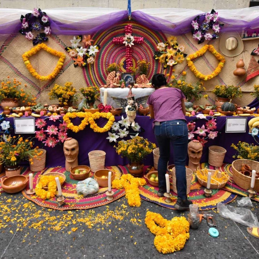 Mujeres instalan ofrenda de día de muertos. Qué día de pone el altar de Día de Muertos.