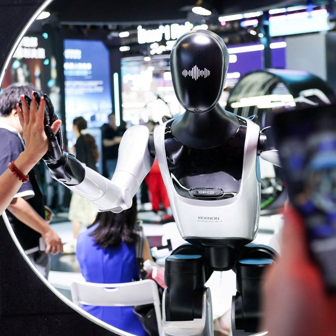 Un visitante choca la mano con un robot humanoide en la Conferencia Mundial de Inteligencia Artificial (WAIC) en Shanghái