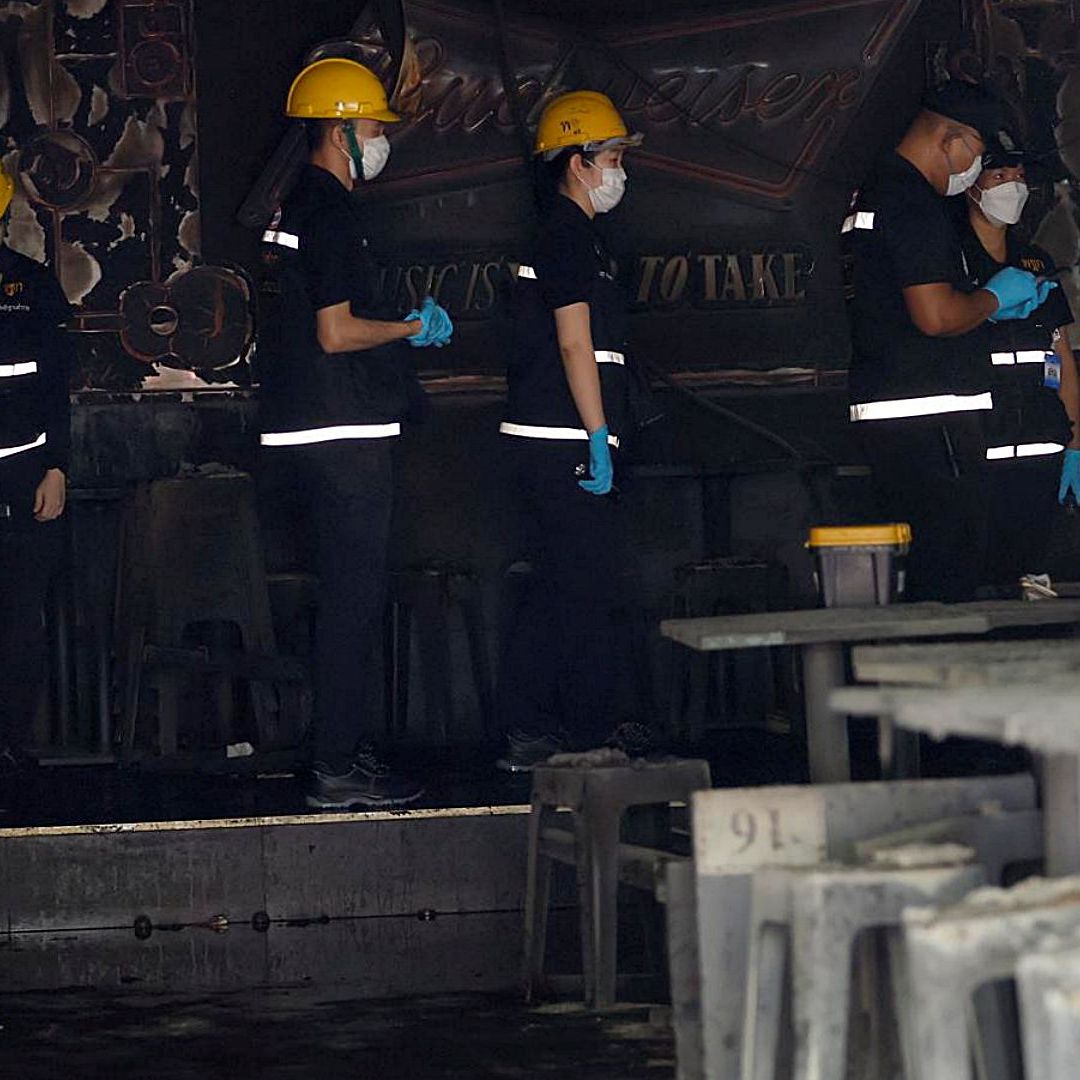 Agentes de la policía forense tailandesa examinan el lugar de un incendio en un bar de Bangkok. Foto: EFE