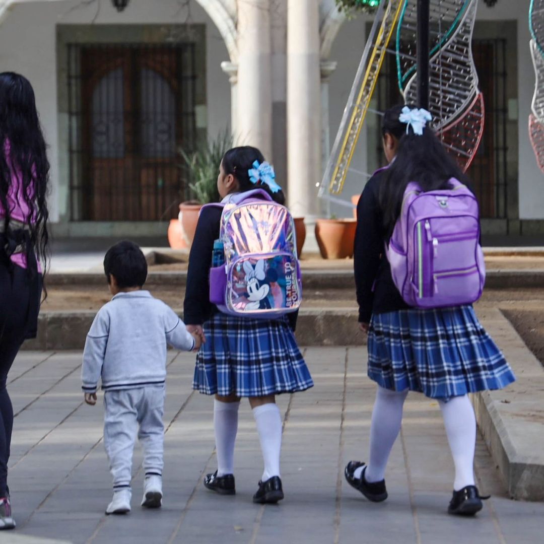 Mujer camina con tres estudiantes de nivel básico