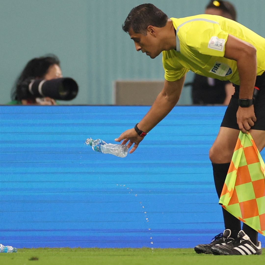 Un abanderado retira botellas de agua lanzadas al campo de futbol