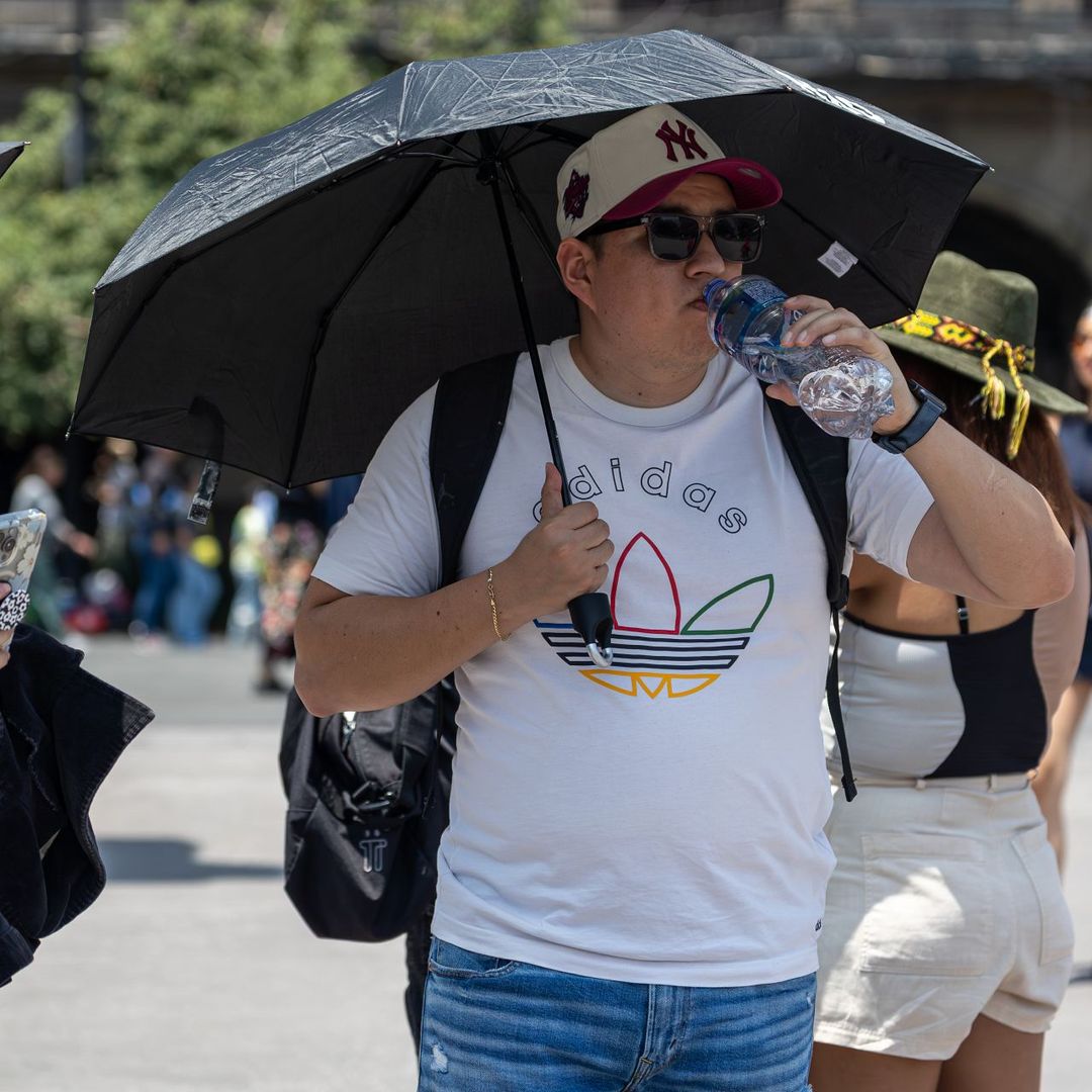 Personas con sombrilla por ola de calor en CDMX
