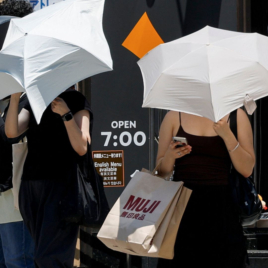 Japoneses usan sombrillas para protegerse del sol