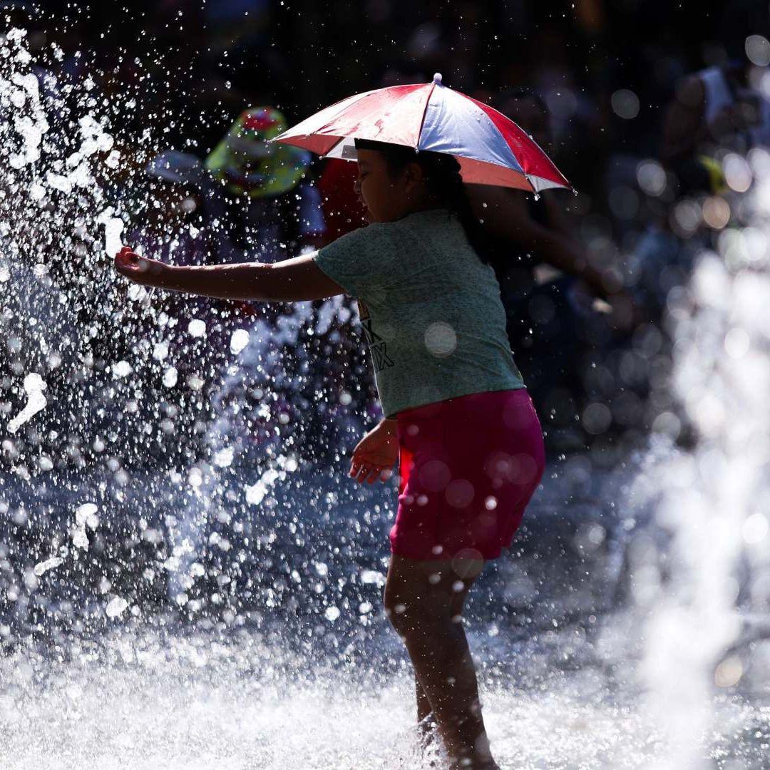 Niña se cubre de los rayos del sol mientras juega en una fuente en CDMX el 29 de abril 2026. Foto: Cuartoscuro