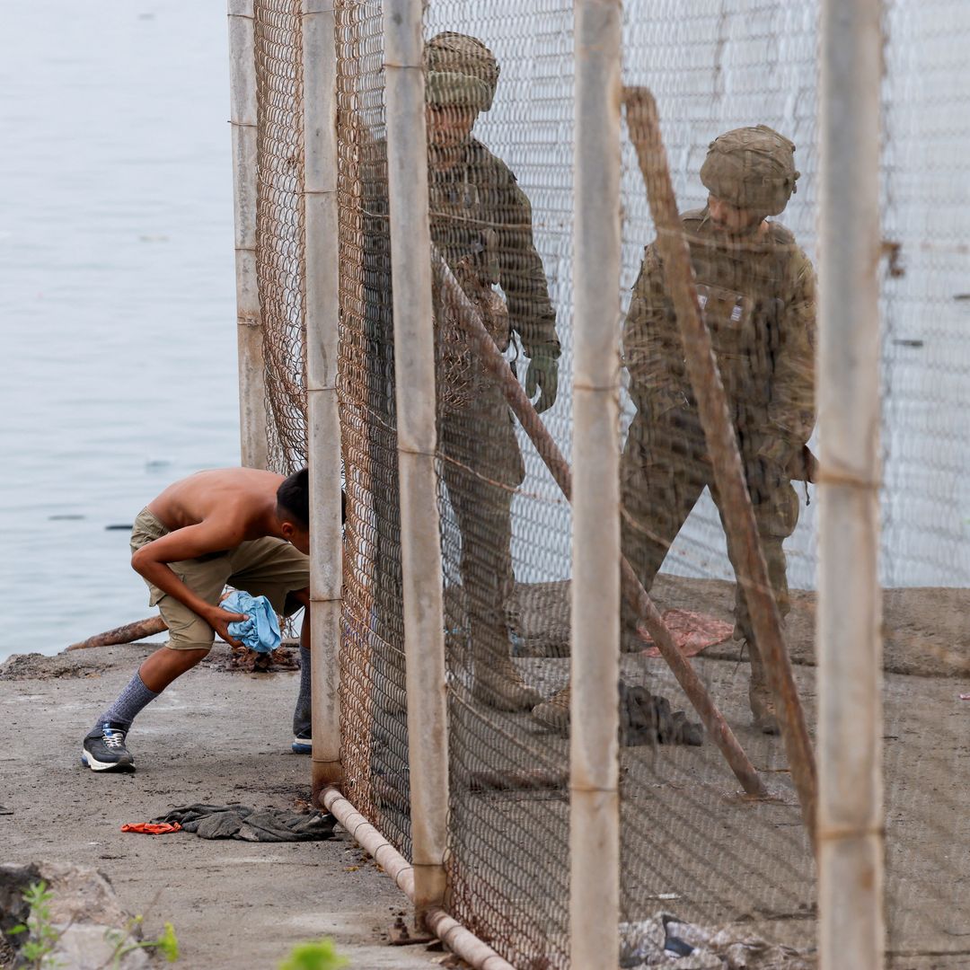 Un joven regresa a Marruecos, atravesando una valla junto a militares de España, el 31 de julio 2026.