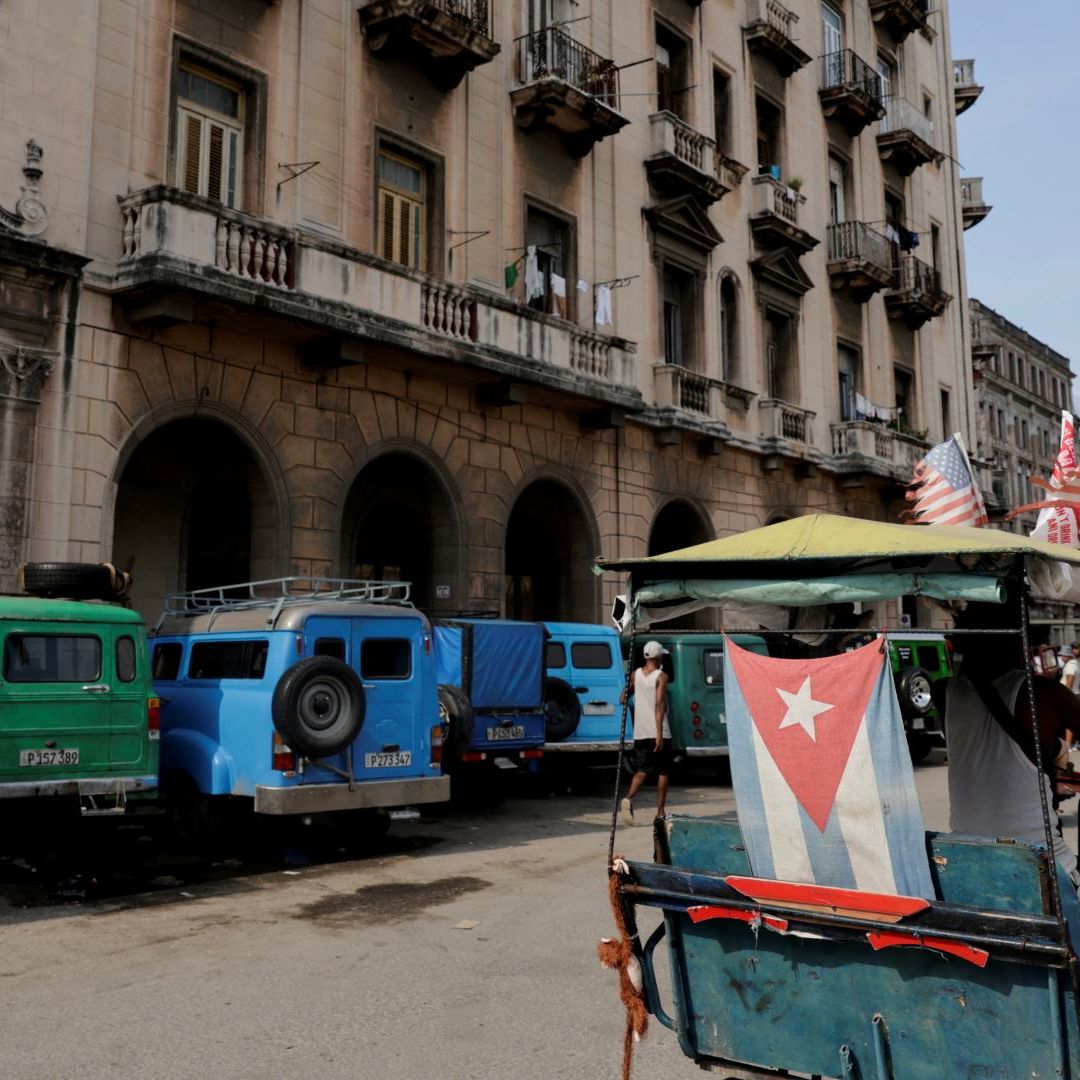 Hombre conduce un bicitaxi junto a automóviles clásicos estacionados en Cuba, el 21 de julio de 2026. Foto: Reuters | Archivo