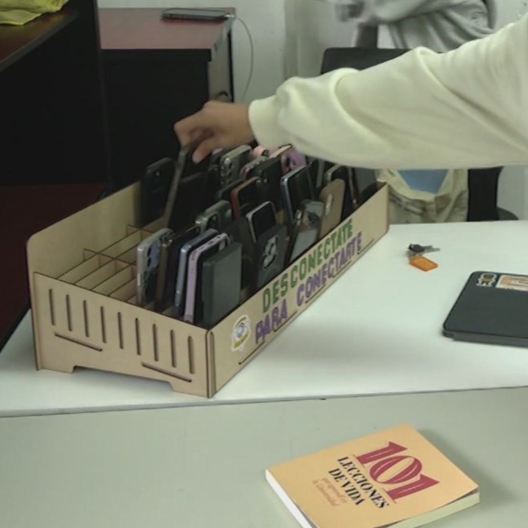 Alumnos dejan su celular en una caja.
