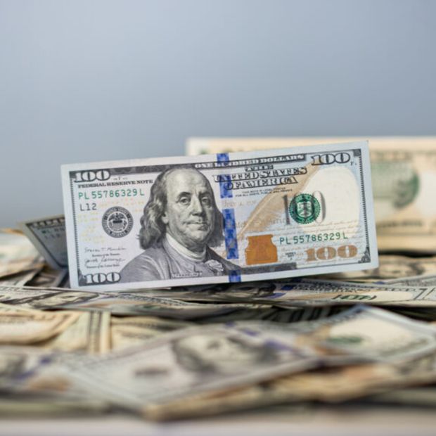 Un billete de 100 dólares sobre una cama de más billetes