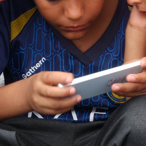 Niños observan un videojuego en el celular, durante su asistencia a la Basílica de Guadalupe en julio 2025. Foto: Cuartoscuro | Archivo