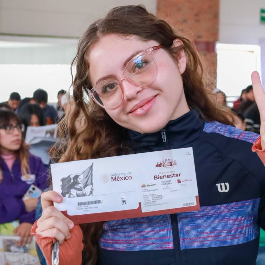 Jovencita posa con sobre donde está Tarjeta en entrega de Tarjetas de Jóvenes Construyendo el Futuro.