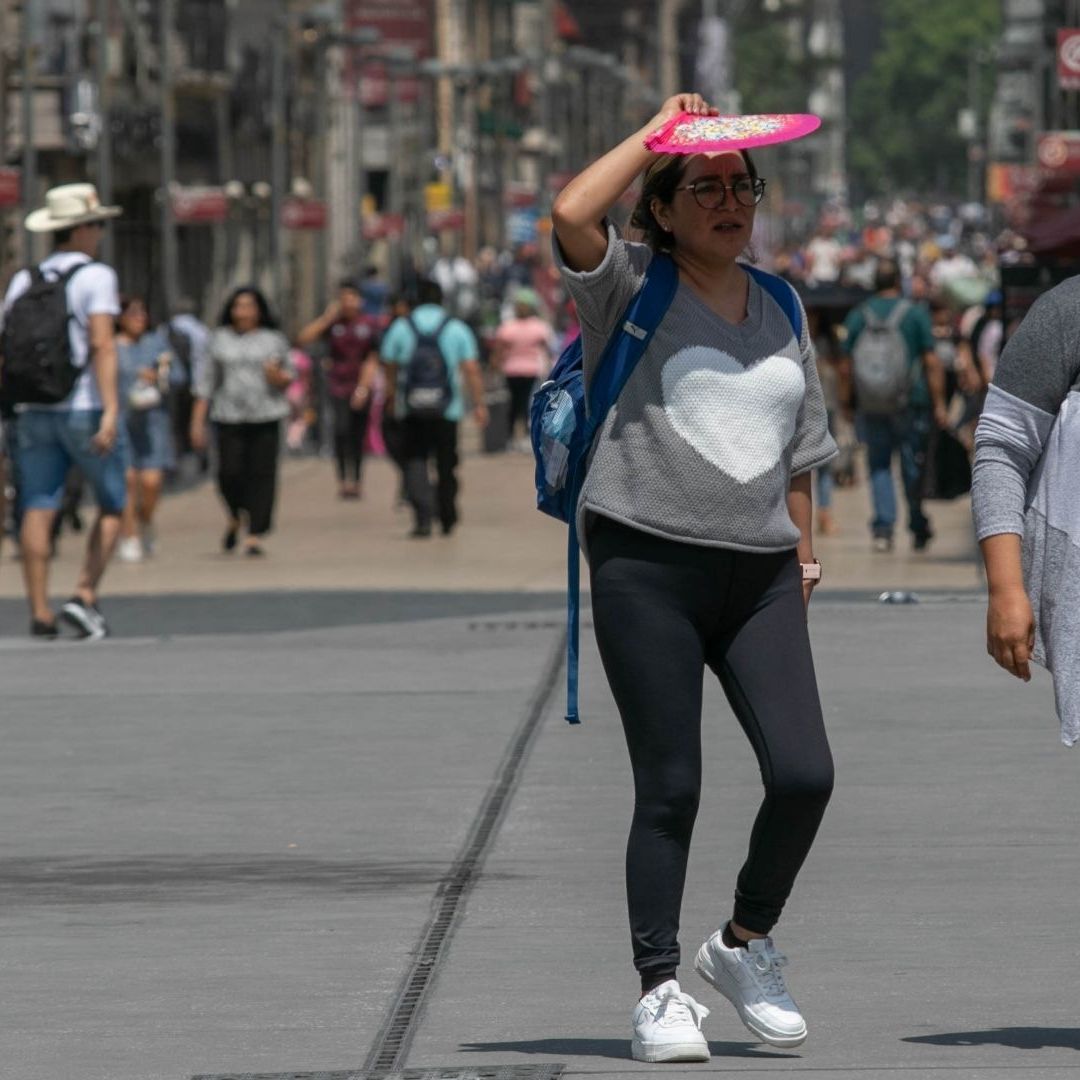 Dos personas caminan bajo el sol en medio de una ola de calor en la CDMX