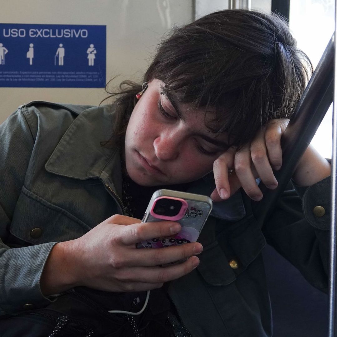 Mujer ve la pantalla de su celular con expresión de cansancio