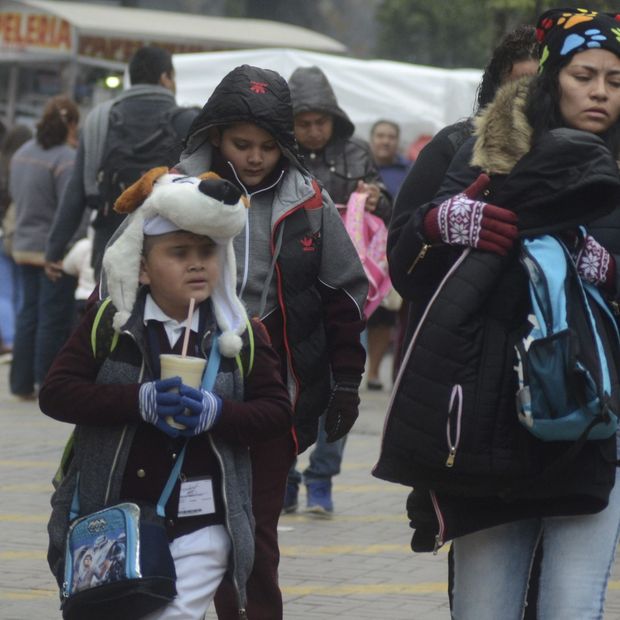 Madre e hijo caminan a la escuela con chamarras y gorros ante bajas temperaturas