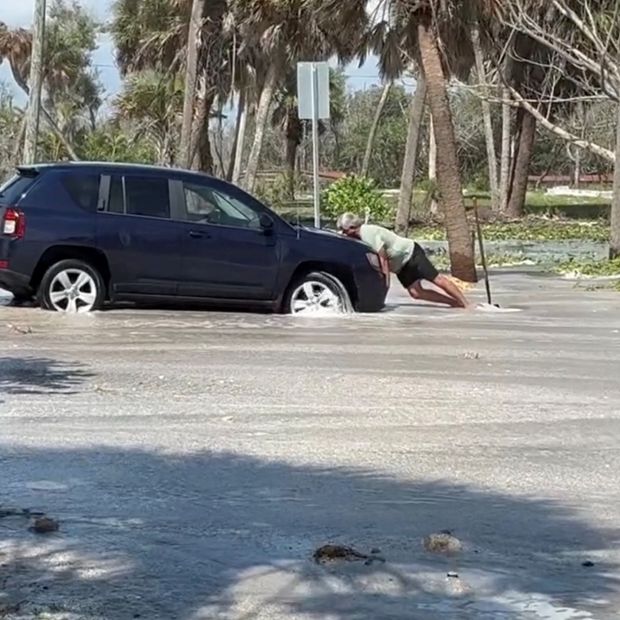 Un hombre intenta sacar su auto de una inundación antes de la llegada de Isaias a Englewood, Florida