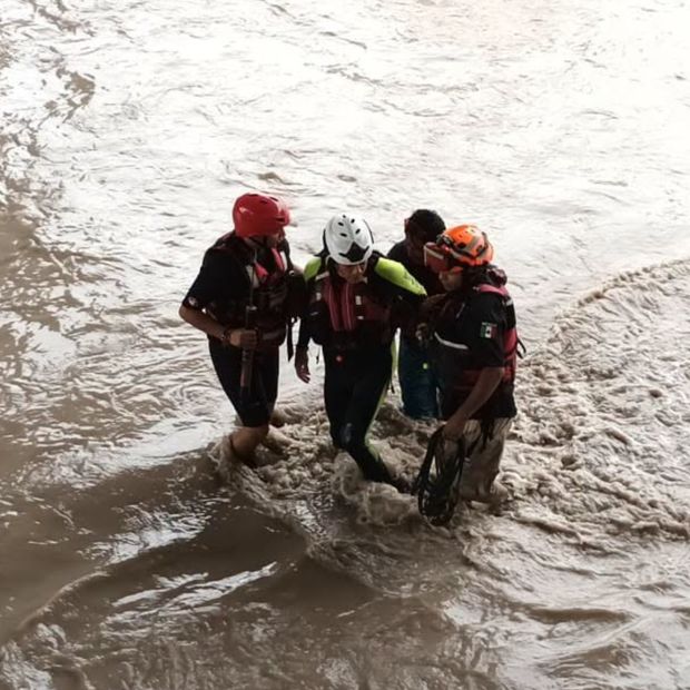 Hombres con chalecos están en medio de una inundación