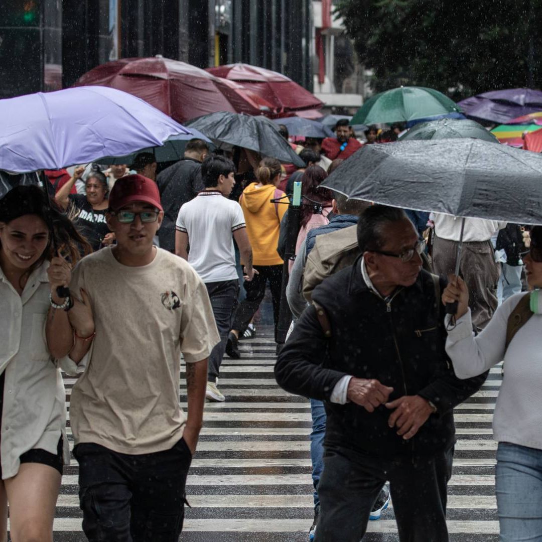 Personas se protegen de la lluvia con paraguas en CDMX.