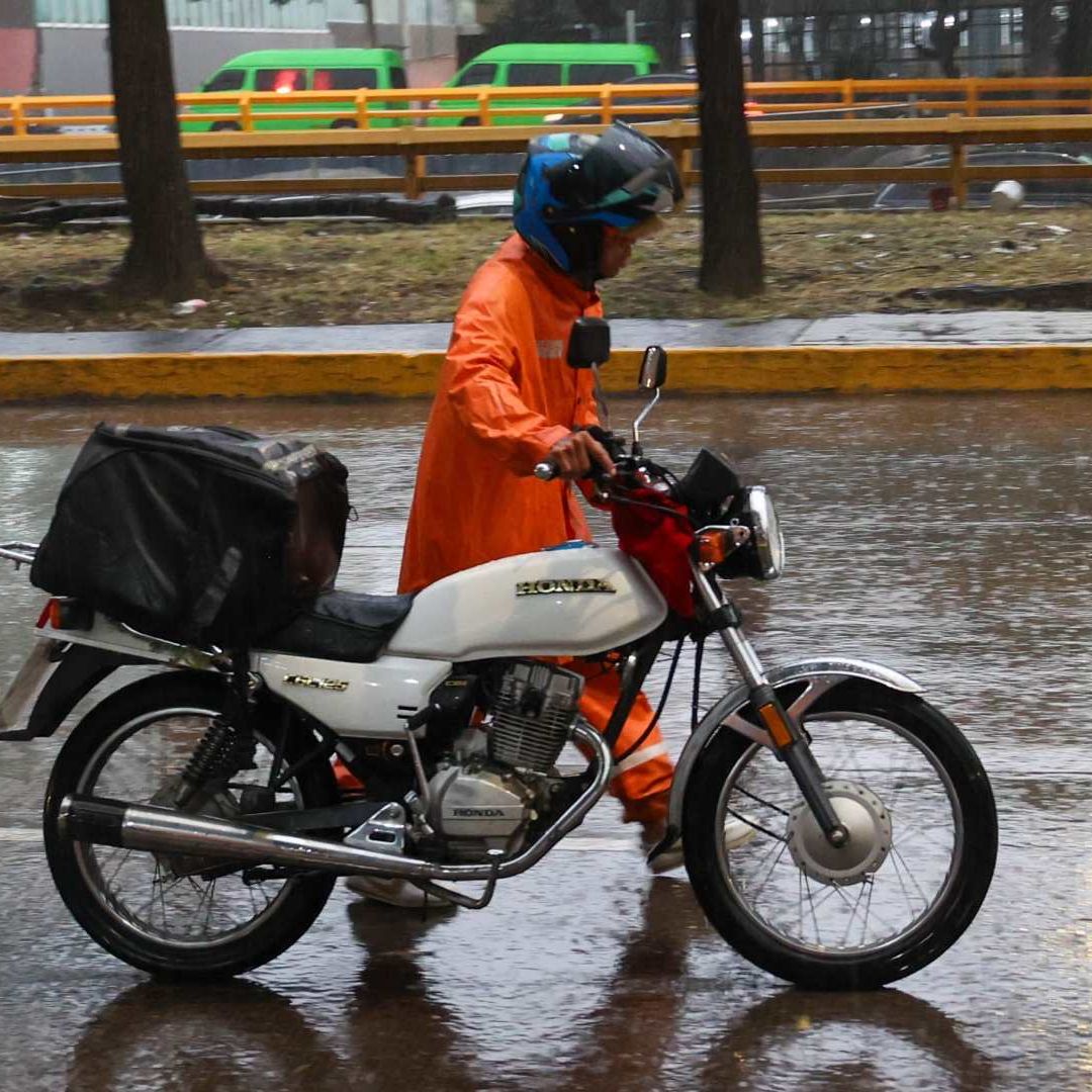 Hombre se protege de la lluvia con un impermeable en Circuito Interior, CDMX, el 19 de agosto 2026. Foto: Cuartoscuro | Archivo