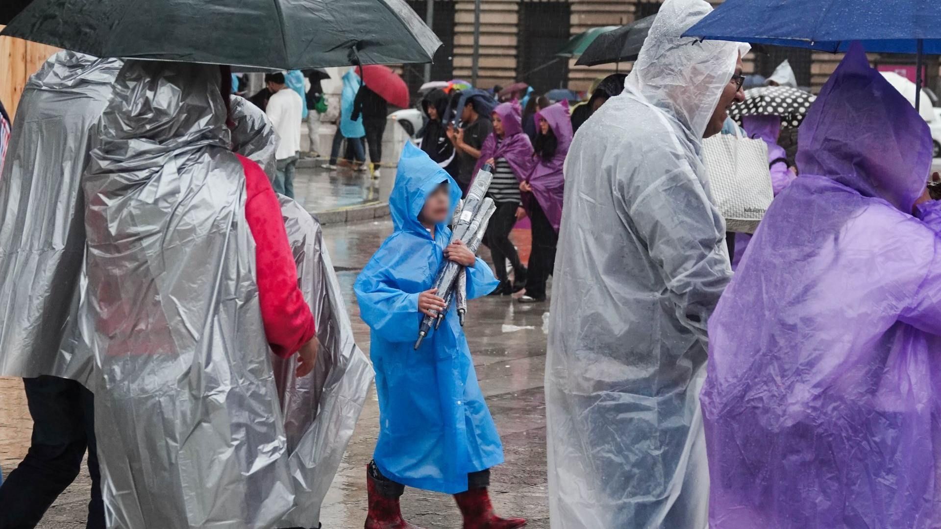 Personas se protegen de la lluvia en la Alameda Central, CDMX
