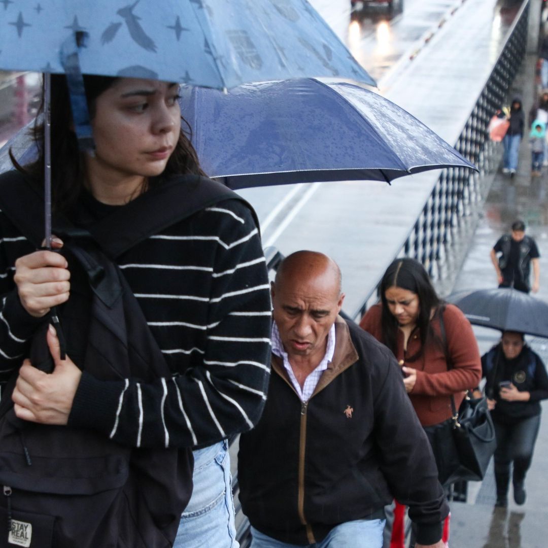 Personas se protegen de la lluvia con chamarras, paraguas e impermeables en estación la Raza del Metro CDMX en julio 2026. Foto: Cuartoscuro | Archivo