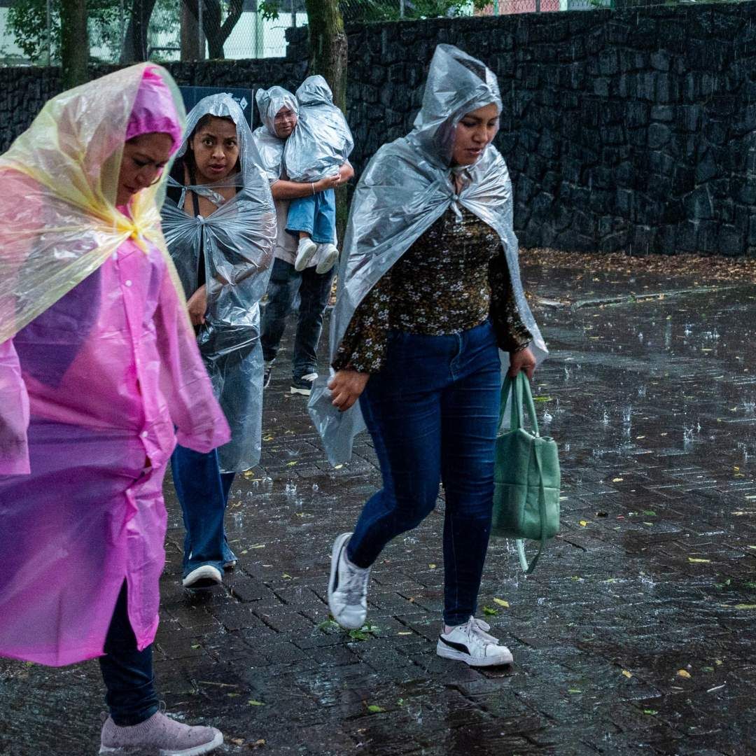 Personas se protegen con impermeables y paraguas ante intensa lluvia en CDMX el 22 de agosto 2026. Foto: Cuartoscuro