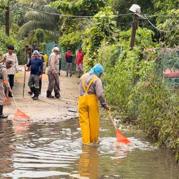 Un grupo de personas realizan limpieza en una calle inundada