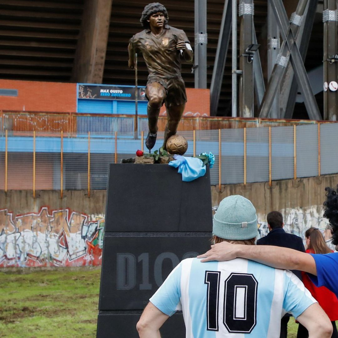 Seguidores de Maradona observan una estatua frente al estadio en Nápoles, Italia. Foto: Reuters