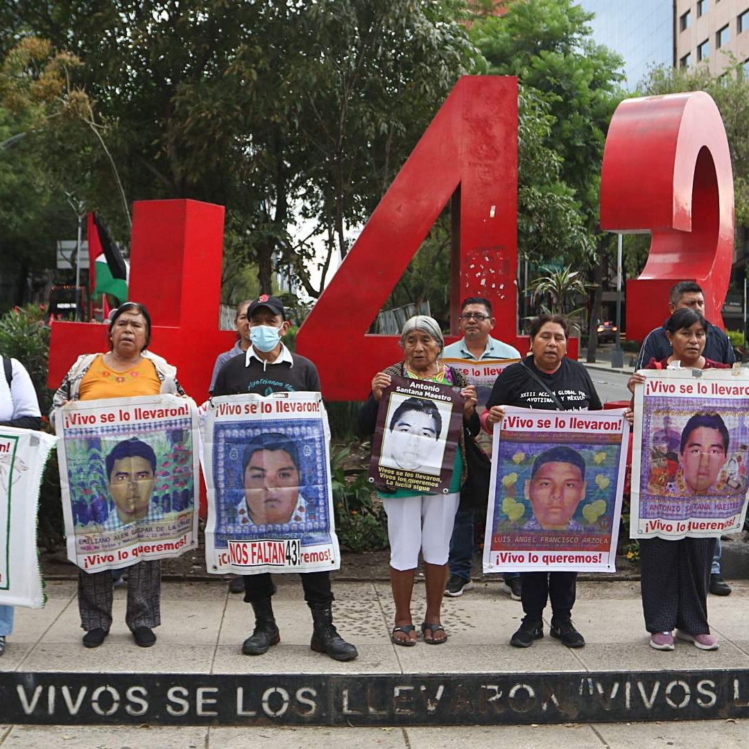 Padres de los estudiantes de Ayotzinapa sostienen carteles con fotos de sus hijos desaparecidos, durante marcha en CDMX en julio 2026