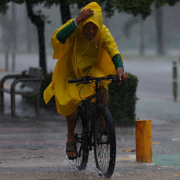 Un hombre conduce su bicicleta en medio de las lluvias provocadas por Simon en Manzanillo, Colima