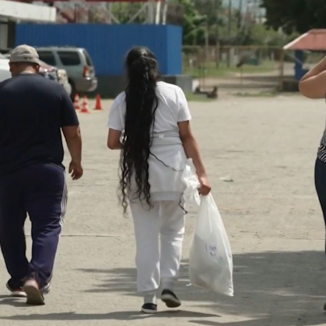Una migrante deportada vestida con ropa blanca y calzado color negro.