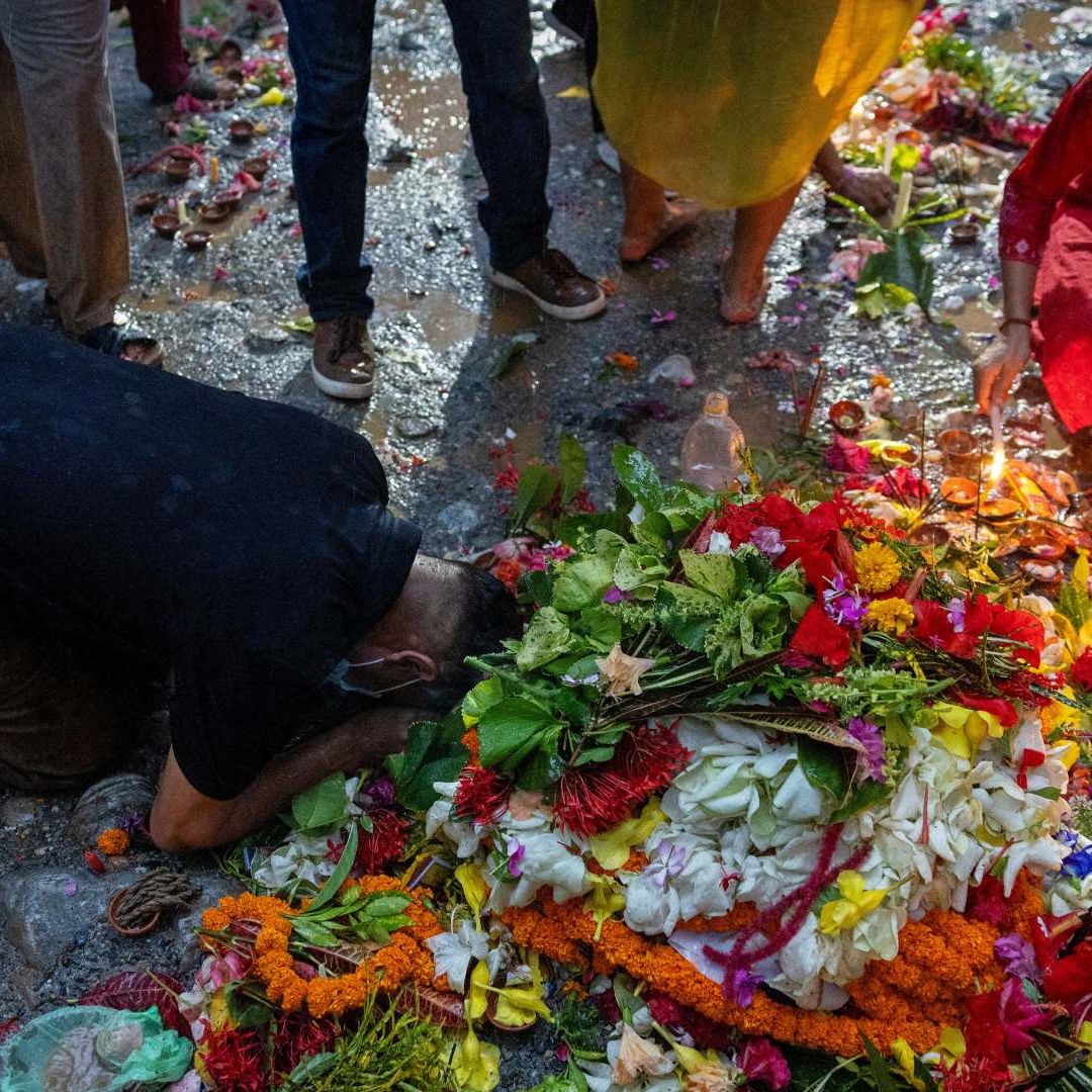 Hombre reza tras depositar una vela y flores en el lugar de enterramiento colectivo luego de inundaciones repentinas en Nepal. Foto: Reuters