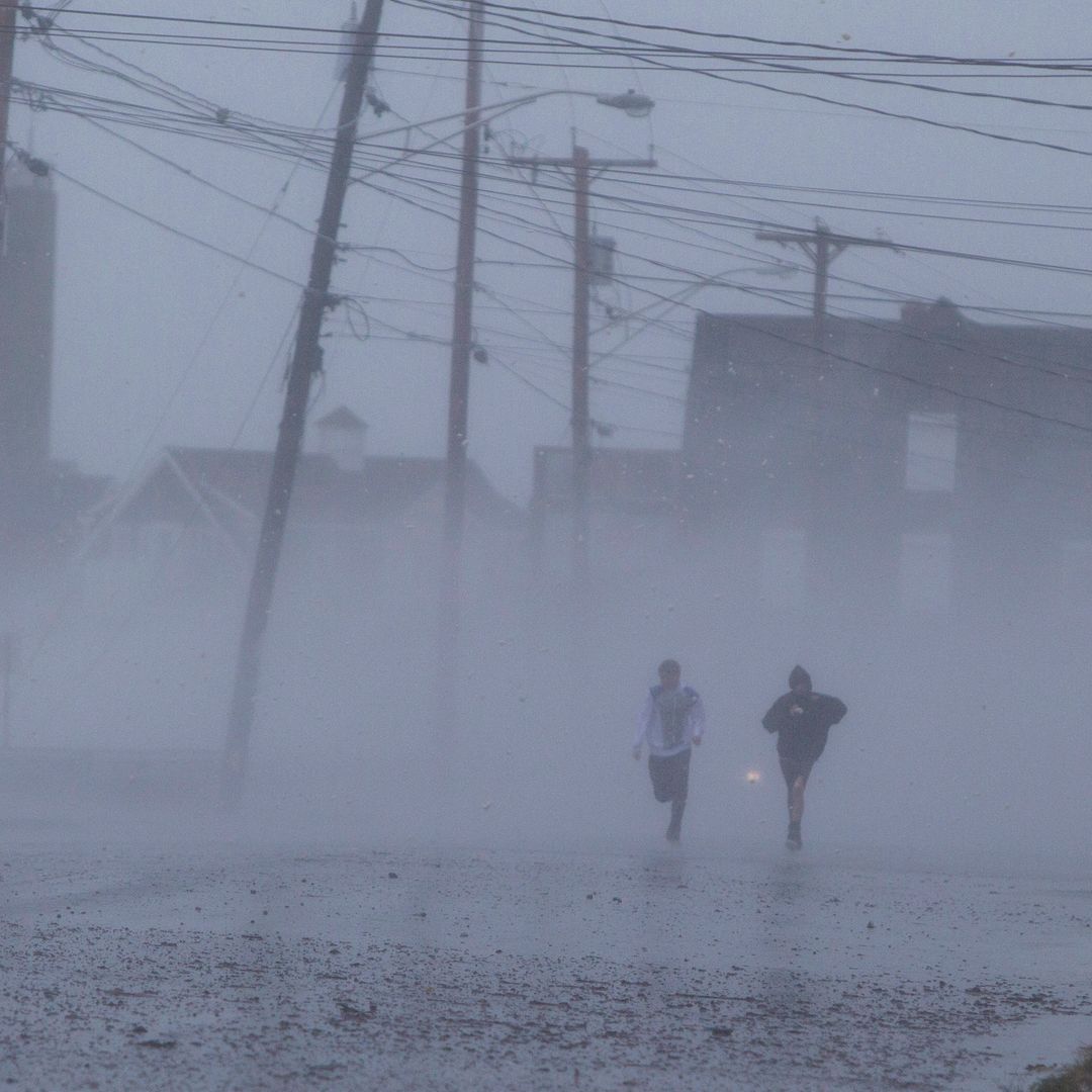 Personas corren bajo lluvias causadas por huracán Sandy en 2012
