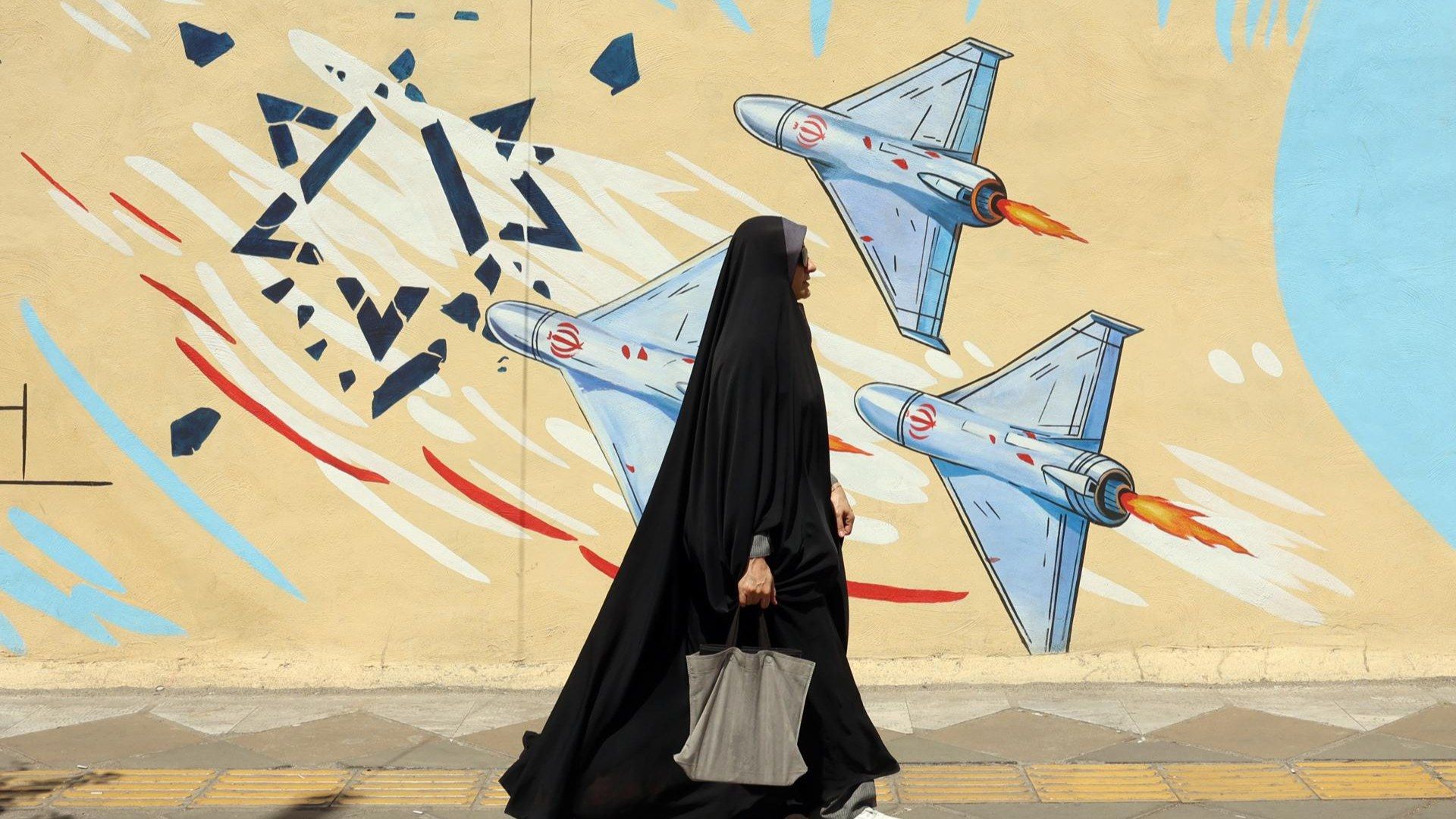 Una mujer pasa delante de un mural contra Israel, en Teherán