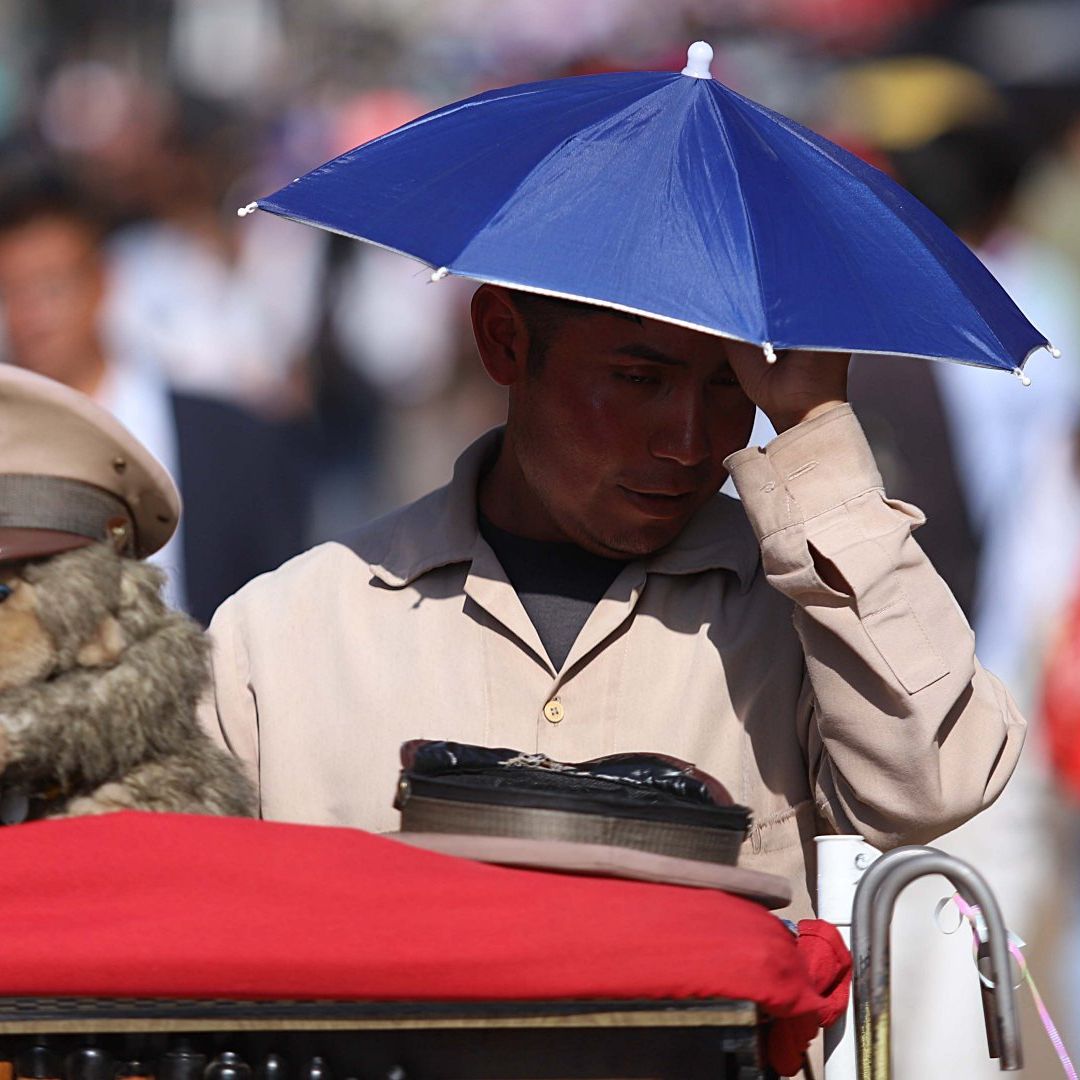 Un organillero se cubre de los rayos del sol con una gorra de sombrilla por ola de calor en CDMX, en abril 2026. Foto: Cuartoscuro | Archivo