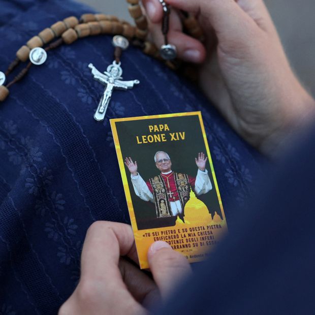 Una mujer sostiene una estampa del papa y un rosario
