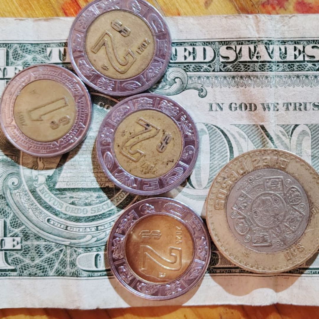 Monedas de pesos mexicanos y un billete de un dólar estadounidense