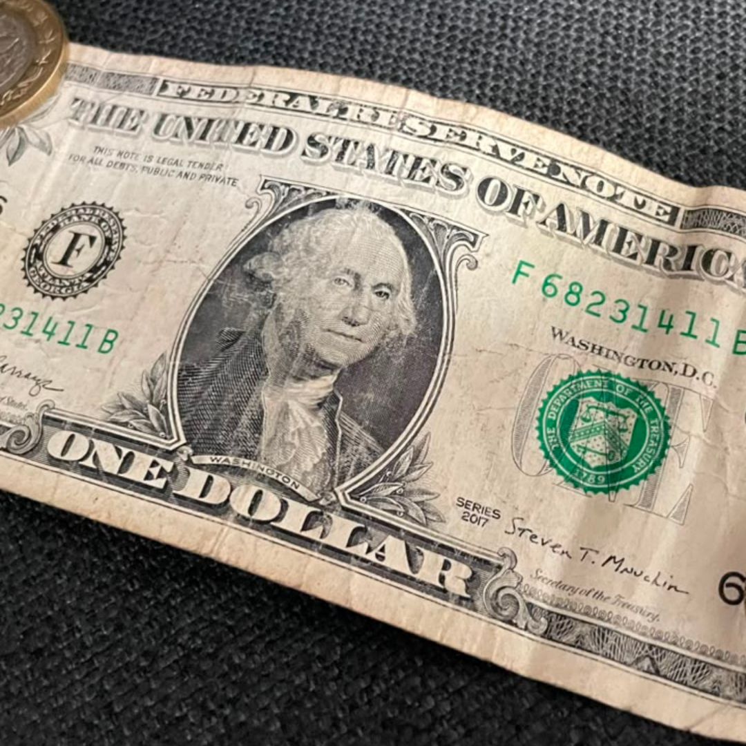 Un billete de un dólar y dos monedas de 10 pesos
