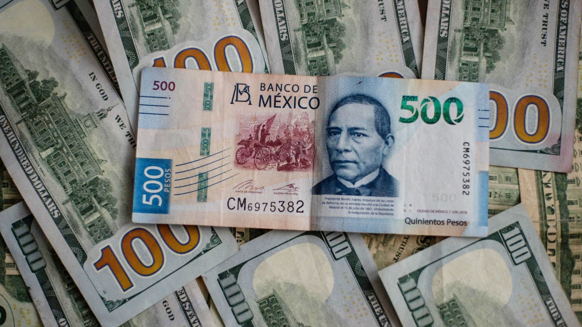 Un billete de 500 pesos sobre billetes de 100 dólares