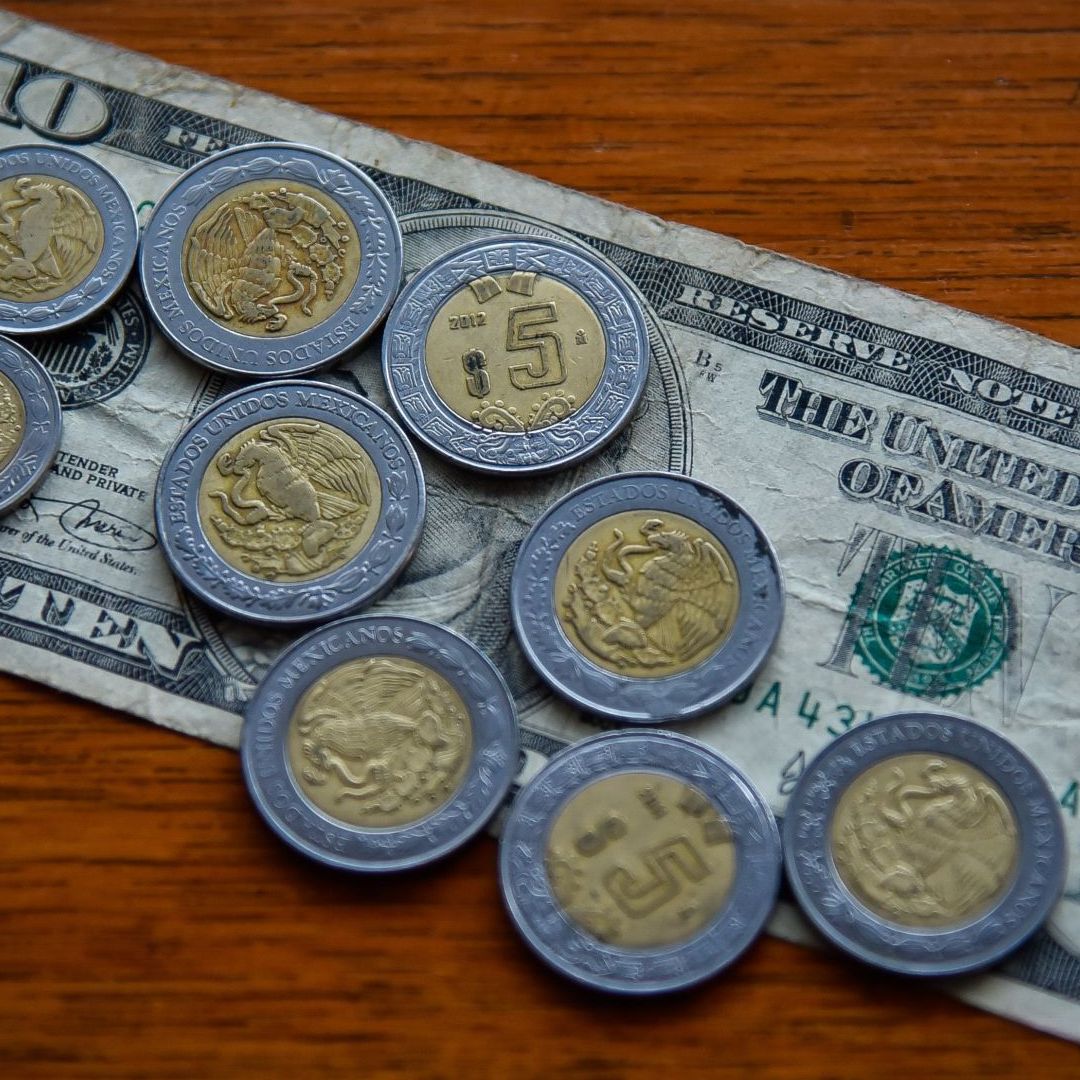 Billete de 10 dólares y monedas de 5 pesos mexicanos