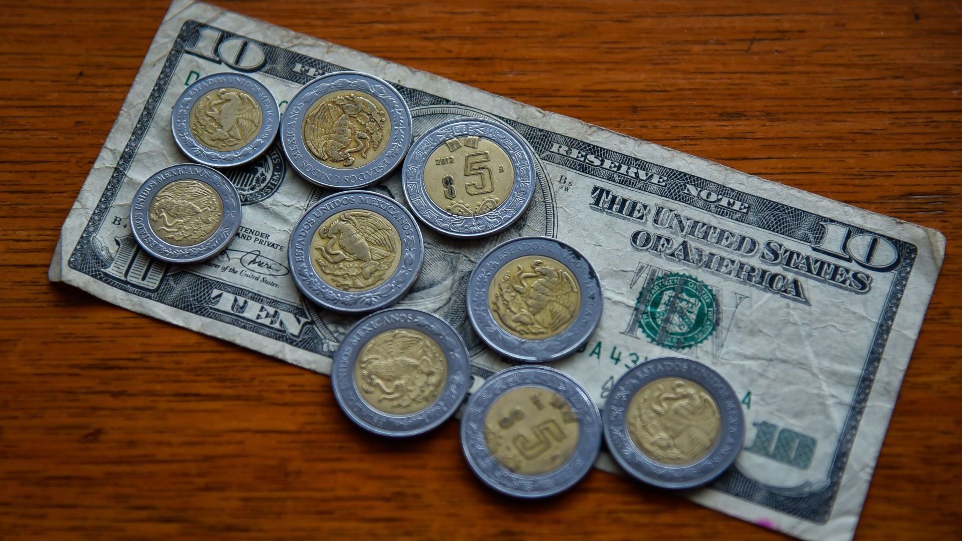 Billete de 10 dólares y monedas de 5 pesos mexicanos