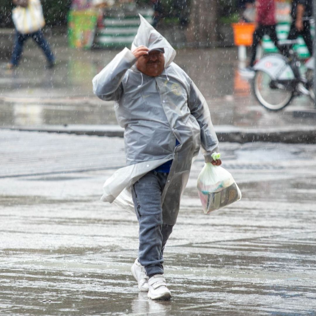 Un hombre camina en medio de una fuerte lluvia en la Ciudad de México