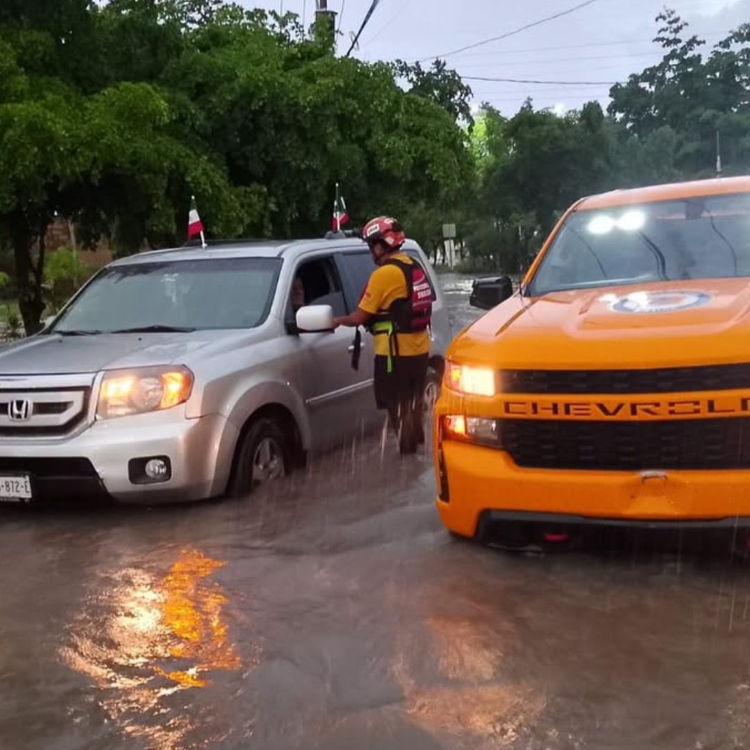 Un elemento de Protección Civil de Sinaloa habla con el conductor de un vehículo durante una inundación en Culiacán