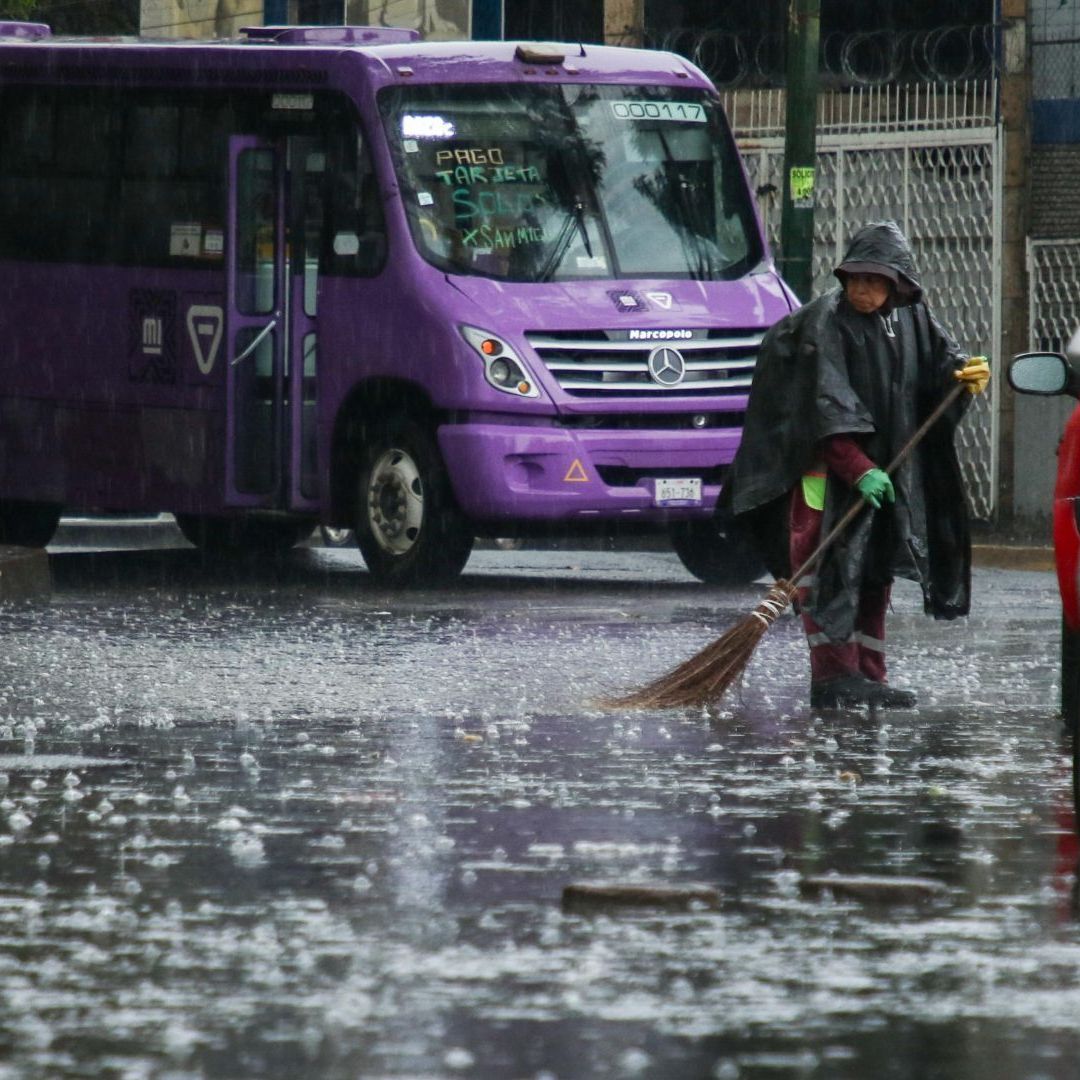 Un trabajador de limpia labora bajo una lluvia intensa en la CDMX