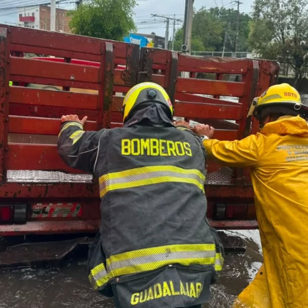 Bomberos empujan una camioneta varada por una inundación en Guadalajara